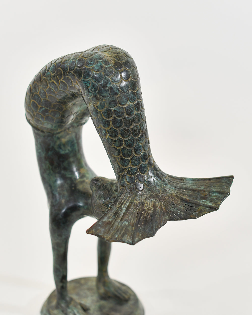 Bronze sculpture of a mermaid with a fish tail on a white background
